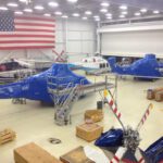 helicopters in hangar encased in blue aircraft shrink wrap ready for shipping