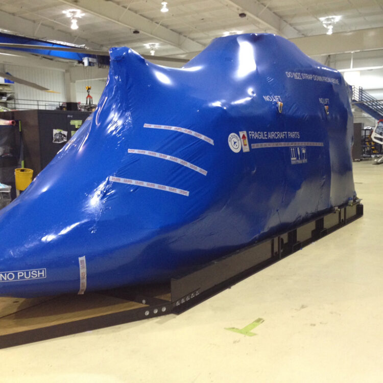 helicopter body encased in blue aircraft shrink wrap secured to a custom steel base