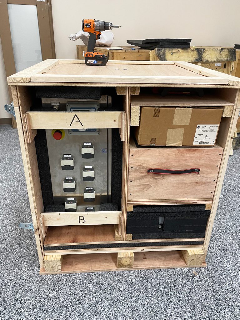 view of labratory automation equipment encased a custom solid wood crate with each component protected in black foam